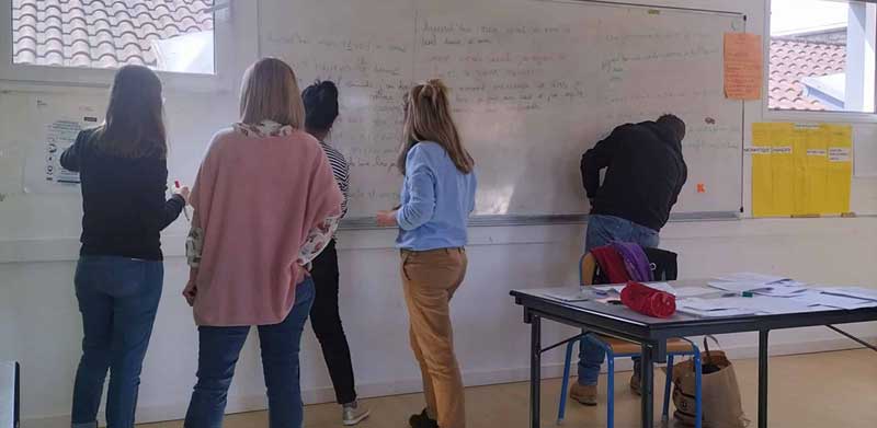Un groupe de personnes devant un tableau blanc dans une salle de classe