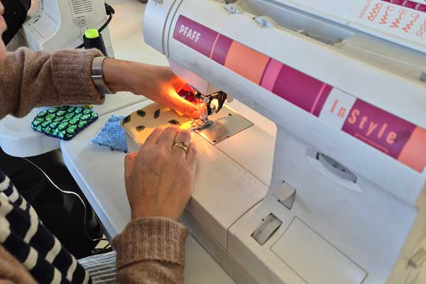 Deux mains de femme dirige le tissu sous l'aiguille d'une machine à coudre